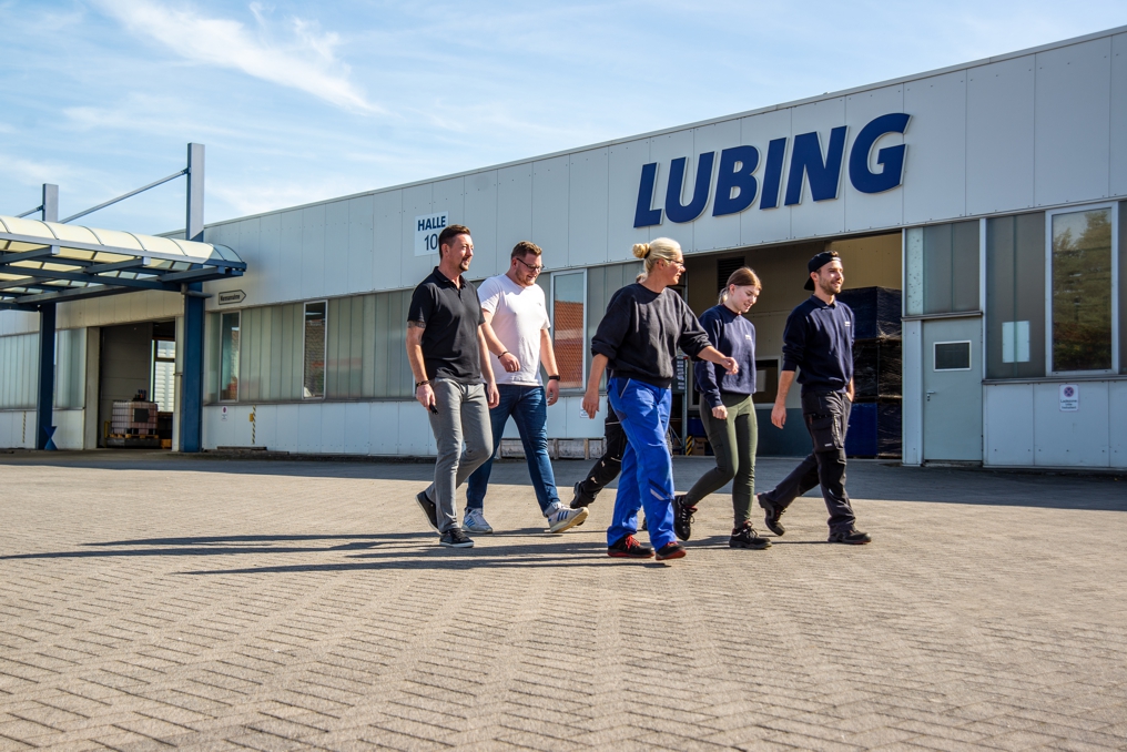 Sechs Mitglieder des LUBING-Teams laufen über das Firmengelände, im Hintergrund das Firmenschild am Gebäude